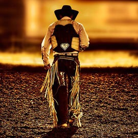 A cowboy seen from behind walking away against a golden backlit dusty landscape, illustrating how to use composition to create compelling photographs
