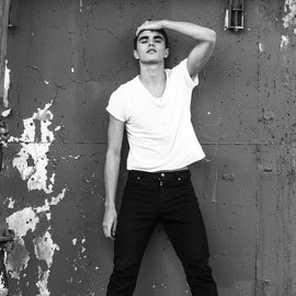 Black-and-white photo of a young man in a white t-shirt leaning against a weathered wall, from a Phlearn Features interview with photographer Grant Legan (Part 2 of 3)