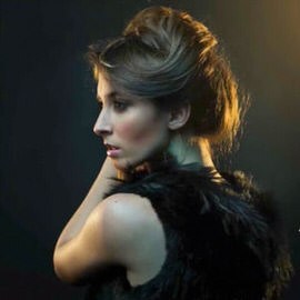 Side profile portrait of a woman with styled hair and a black fur wrap lit against a dark background, illustrating a trick to recover shadow detail in Photoshop