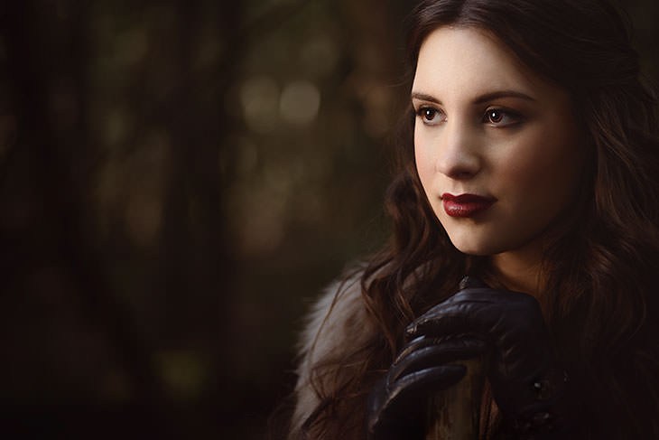 Dark, moody portrait of a woman with long dark hair in dim lighting