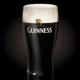 A pint glass of Guinness stout beer with condensation and a creamy head against a dark background, illustrating how to make beer look amazing in Photoshop (Part 1)