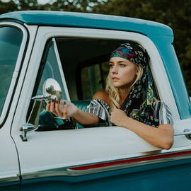 Woman in a headscarf leaning out of a vintage blue truck window with branded logos removed from the vehicle, example for removing distracting logos in Photoshop