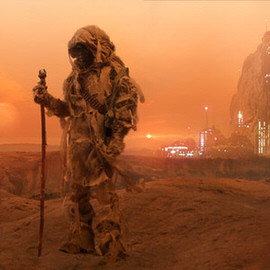 Robed hooded figure holding a staff standing on a dune overlooking a glowing orange desert cityscape at dusk, example for creating an epic composite called A Dark Force