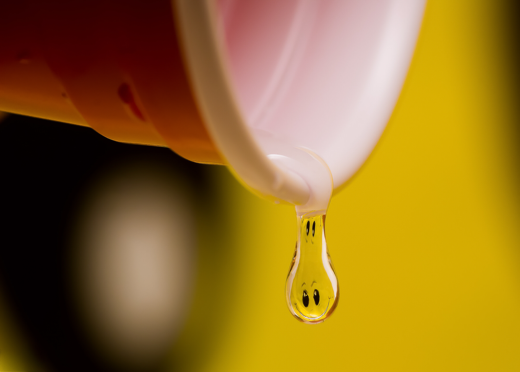 Water drop photography ideas, Pour Me Some Happy: macro of a water drop falling from the rim of a pink cup, a yellow smiley face refracted inside the drop