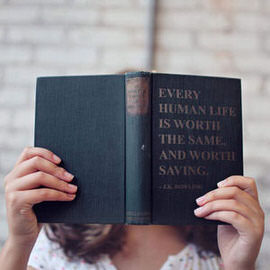 Person holding an open book in front of their face with realistic embossed text reading a quote about human life, example for adding realistic text to anything in Photoshop
