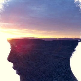 Silhouette of a person's head double-exposed with a sunset over rocky coastal cliffs, example for creating a double exposure video in Photoshop