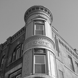 Black and white photo looking up at an ornate Victorian corner tower with round turret windows and decorative stonework, example for 5 tips for stunning black and white photography