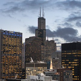 Chicago skyline at dusk with illuminated skyscrapers under a cloudy sky, example for mastering Adobe Camera RAW in Photoshop