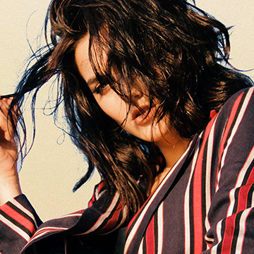 Woman with tousled dark hair in a red and black striped robe against a cream background, example for creating better cut-outs for compositing