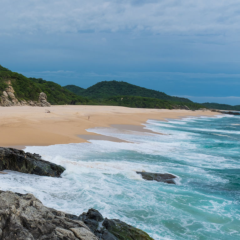 Aerial view of ocean waves crashing against dark rocks along a sandy beach, example photo for the Color Space Explained tutorial (sRGB, Adobe RGB, ProPhoto RGB)