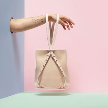 Cream leather bucket bag hanging in front of pink and green geometric backdrop, example for shooting product photography and background retouching