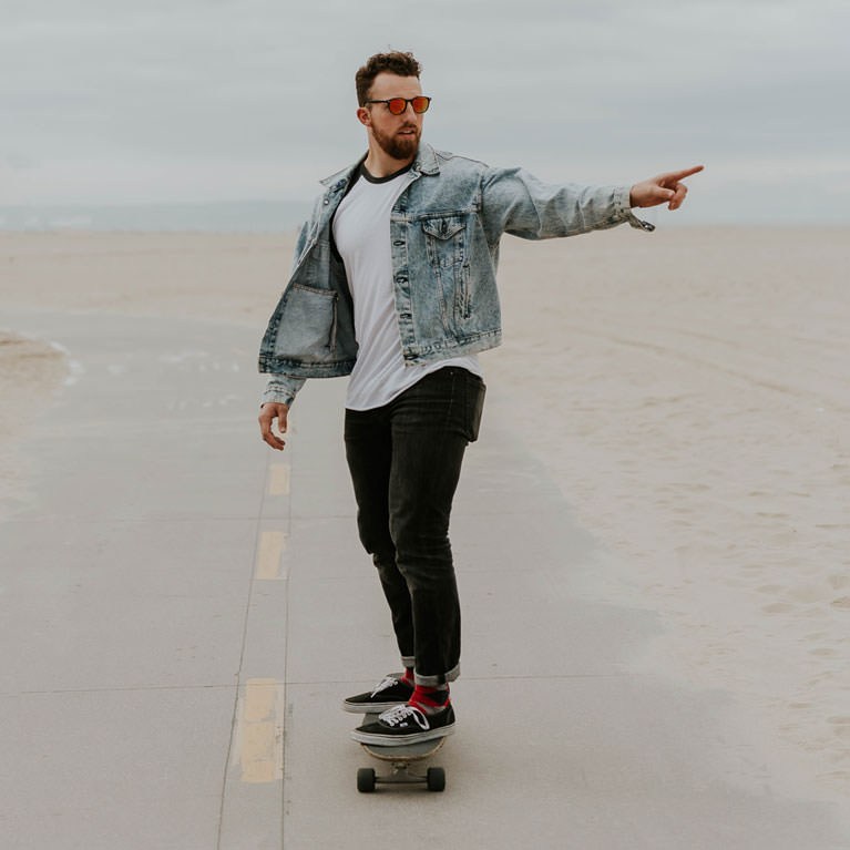 Close-up of a skateboarder's legs and sneakers riding down a paved road with lane markings, example for quickly removing distractions in Photoshop