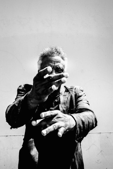 Black-and-white portrait of Donald Byrd with one hand raised over his face and the other held out below