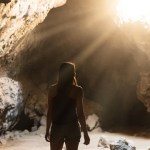 Silhouette of a woman in a sunlit cave with light rays streaming in