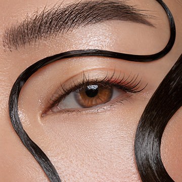 Extreme close-up of a woman's eye and eyebrow with heavy digital retouching lines showing the beauty retouching process in Photoshop