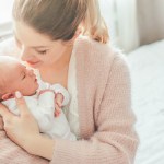 Mother in a pink cardigan holding her newborn baby, edited with the Family presets