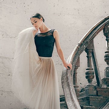 Woman in a dark top leaning against an old staircase rendered with a muted teal color grade, demonstrating advanced color grading in Lightroom Classic