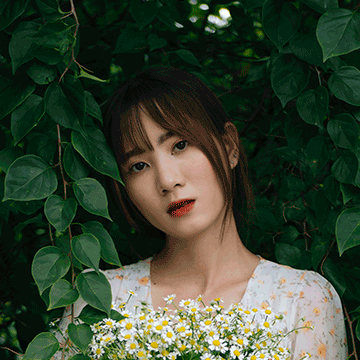 Woman holding white daisies against a backdrop of green leaves, illustrating 10 tips for using layer masks in Photoshop