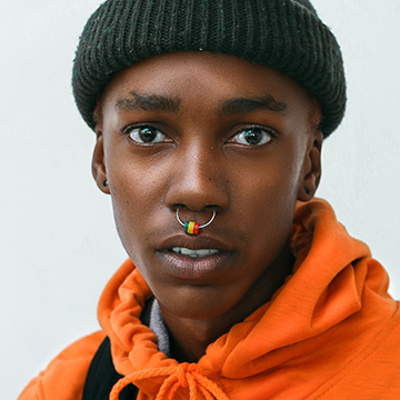 Portrait of a young man in an orange hoodie and beanie against a plain background, demonstrating how to dodge and burn in Lightroom Classic