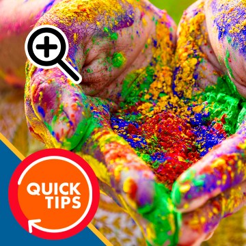 Hands cupped and covered in colorful powder pigment, with a magnifying glass icon overlay, demonstrating how to zoom in and zoom out in Photoshop