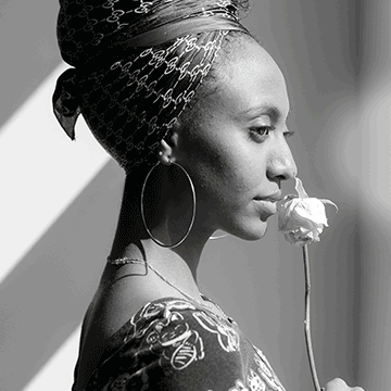 Black and white profile portrait of a woman in a headwrap smelling a rose, demonstrating Photoshop's Colorize neural filter for adding color to black and white photos