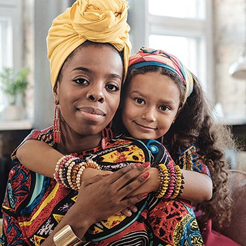Mother and daughter in colorful headwraps and patterned outfits embracing indoors, demonstrating how to edit family photos in Lightroom Classic