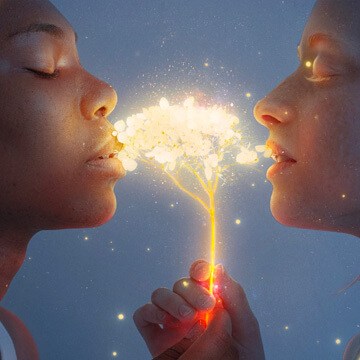 Two faces close together with glowing golden light and floral sparkles between them, demonstrating how to create a glow effect in Photoshop