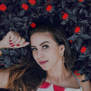 Woman lying among dark foliage with red flowers, demonstrating how to change the color of plants and foliage in Photoshop