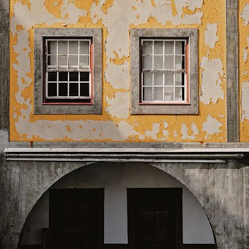 Weathered building facade with peeling paint and textured stucco, demonstrating removing objects from complex textures in Photoshop