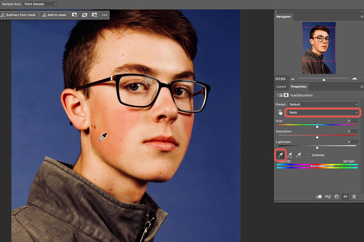Hue/Saturation panel set to Reds with the eyedropper sampling red skin on a young man's cheek to remove redness from skin in Photoshop