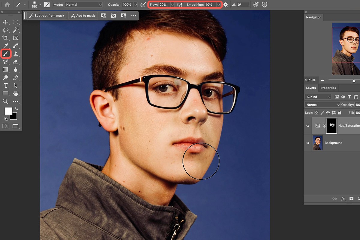 Brush tool at 20 percent flow painting white on the inverted Hue/Saturation mask over a man's cheek to reveal the redness correction