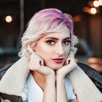 Close-up portrait of a woman with pastel pink-toned hair wearing a shearling jacket, thumbnail for a tutorial on changing a hairstyle using AI in Photoshop
