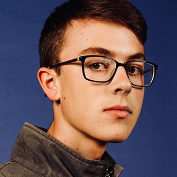 Close-up portrait of a man wearing glasses, thumbnail for a tutorial on removing redness from skin in Photoshop