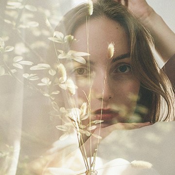Double-exposed portrait of a woman blended with white flowers, thumbnail for a tutorial on creating a double exposure effect in Photoshop