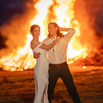 Bride and groom embracing in front of a bonfire, thumbnail for the beginner's guide to wedding photo editing in Lightroom