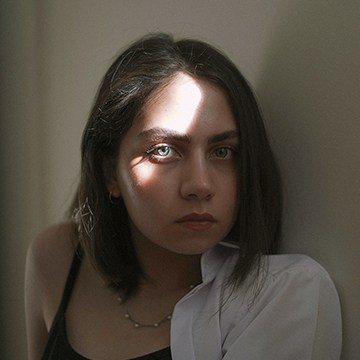 Portrait of a woman with a dramatic light streak across her face, thumbnail for a tutorial on correcting white balance in Photoshop