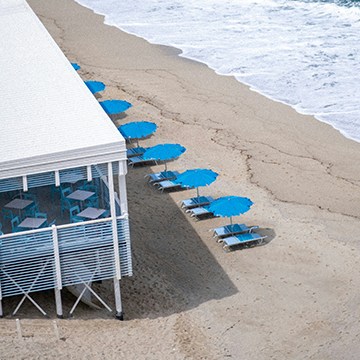 Aerial view of white beach cabanas and umbrellas along the shore, thumbnail for a tutorial comparing Generative Fill, Clone Stamp and Spot Healing Brush