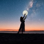 Silhouette of a woman reaching for a glowing moon under a starry sky