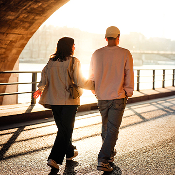 Couple standing under a bridge silhouetted against golden sunset light, thumbnail for a tutorial on the fastest way to great photos in Photoshop and Lightroom