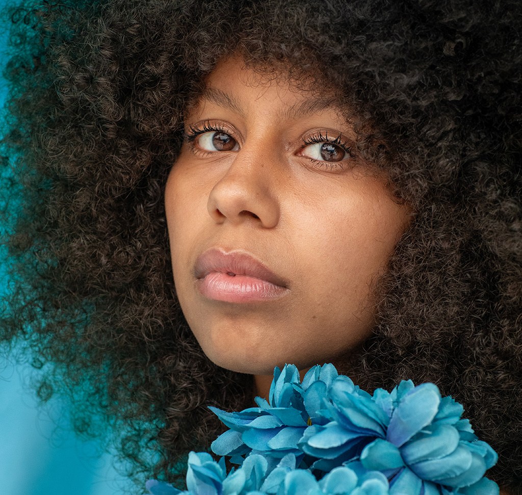 The same portrait after the Lightroom Classic edit, with skin tone smoothed and the eyes drawing focus while the blue flowers stay soft