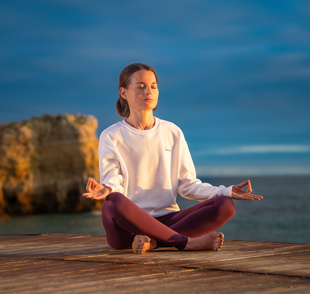 The same seated meditation portrait on a dock with warmer, brighter light after mobile editing.