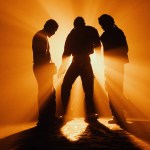 Three people silhouetted against orange light