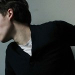 A young man in a black jacket turning his head