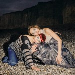 A woman lying on a rocky shore at night