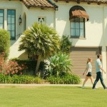 A couple walking past a Spanish-style house