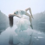A woman in a white dress levitating over misty water
