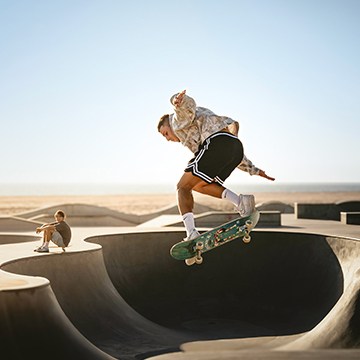 A skateboarder mid-jump trick at an outdoor skate park under a clear blue sky — The Power of Masking & Coloring in Lightroom tutorial thumbnail
