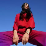 A woman in a red outfit against a blue sky