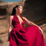 A woman in a red dress sitting on red rock