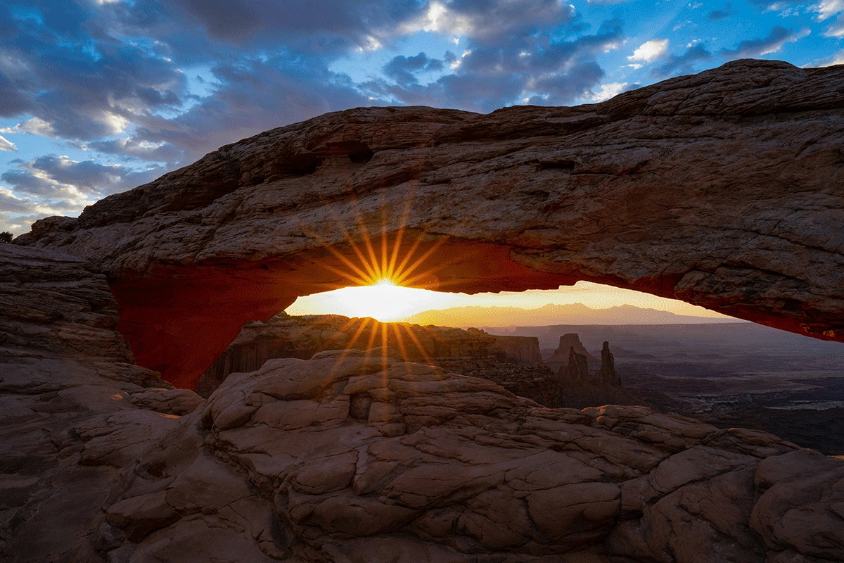 Mesa Arch at sunrise under a blue sky